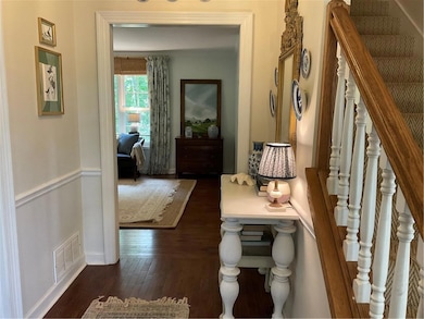 Hallway with dark wood-style flooring, stairway, and baseboards