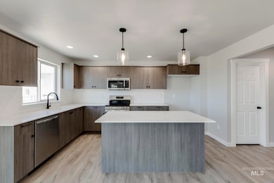 Kitchen featuring decorative light fixtures, a kitchen island, appliances with stainless steel finishes, modern cabinets, and recessed lighting