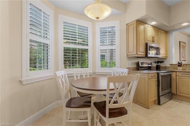Kitchen with appliances with stainless steel finishes, dark stone counters, pendant lighting, light brown cabinets, and light tile patterned flooring