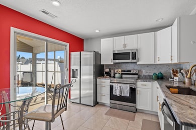 Kitchen featuring white cabinetry, sink, tasteful backsplash, and stainless steel appliances