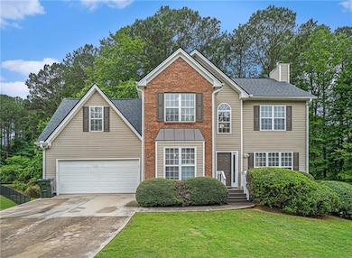 Traditional home featuring driveway, a chimney, roof with shingles, a garage, and brick siding