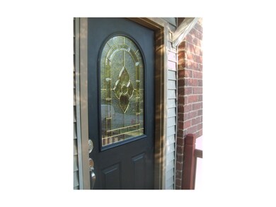 Elegant front door accented by brick trim and low maintenance vinyl siding