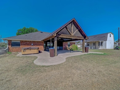 Rear view of property with a hot tub, a patio, and