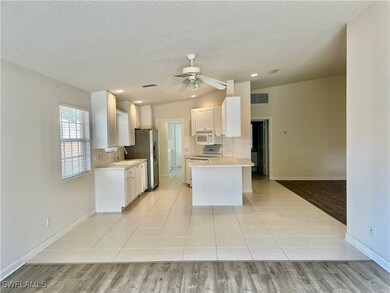 Kitchen featuring white appliances, ceiling fan, l