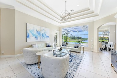 Living room with a notable chandelier, a tray ceiling, ornamental molding, and light tile patterned flooring