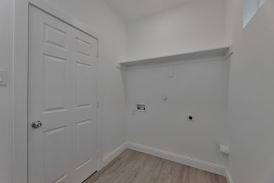 Laundry room featuring light wood-style floors, hookup for a gas dryer, electric dryer hookup, and hookup for a washing machine