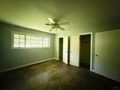 Unfurnished bedroom featuring multiple closets, concrete flooring, and ceiling fan