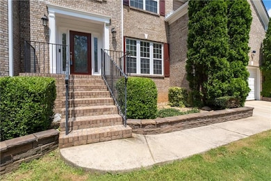 Doorway to property featuring brick siding, a garage, and concrete driveway