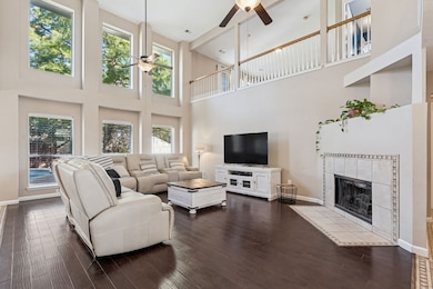 Living area with a tiled fireplace, a high ceiling, dark wood-type flooring, and a ceiling fan