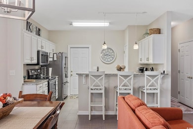 Kitchen featuring appliances with stainless steel finishes, white cabinetry, and hanging light fixtures
