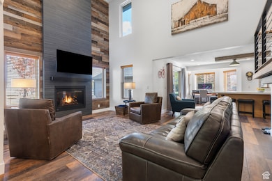 Living room with wood finished floors, a large fireplace, and a high ceiling