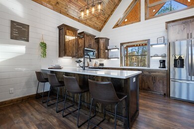 Kitchen with kitchen peninsula, wooden walls, high vaulted ceiling, and stainless steel appliances