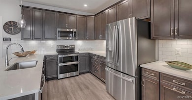 Kitchen with dark brown cabinetry, a sink, light w