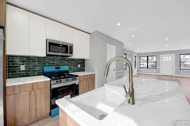 Kitchen with stainless steel appliances, modern cabinets, white cabinetry, light wood finished floors, and recessed lighting