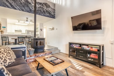 Living area featuring a wood stove, light wood-style floors, and a ceiling fan