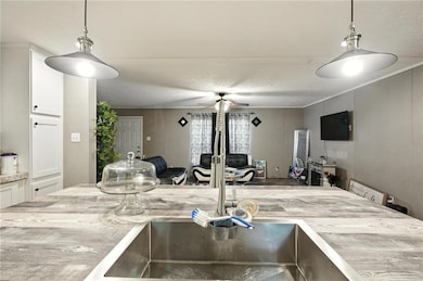 Kitchen with ceiling fan, open floor plan, white cabinets, and light countertops