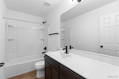 Bathroom featuring shower / tub combination, vanity, and dark wood-style flooring