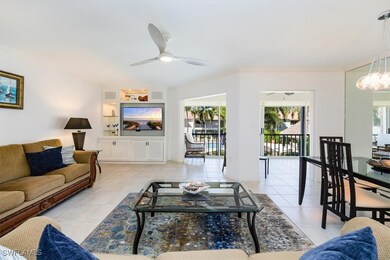 Living room with light tile patterned flooring, ceiling fan with notable chandelier, and visible vents