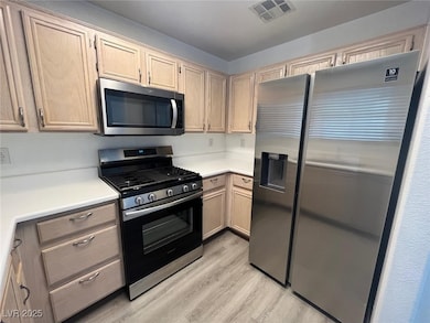 Kitchen with stainless steel appliances, light woo