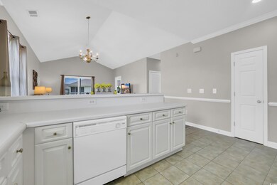 Kitchen featuring white dishwasher, a chandelier, light tile patterned floors, white cabinetry, and light countertops