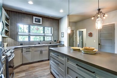 Over the sink windows allow for daylight and view out the front of this home