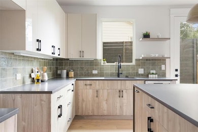 Kitchen with light brown cabinets, plenty of natural light, light wood-style floors, and dark countertops