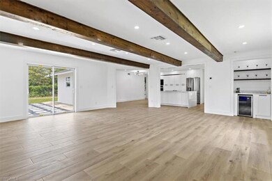 Unfurnished living room with beverage cooler, beam
