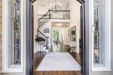 Entrance foyer with stairs, a chandelier, wood finished floors, and a towering ceiling