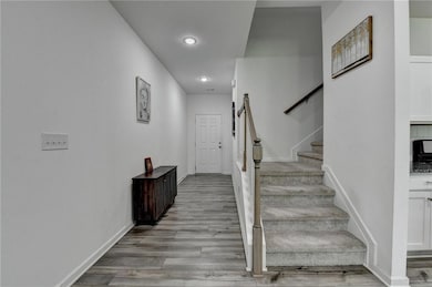 Stairs with wood finished floors, baseboards, and 