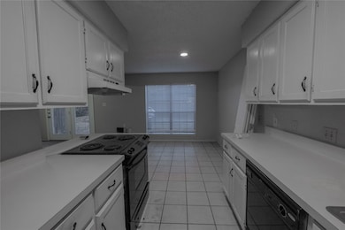Kitchen featuring black appliances, white cabinetry, light countertops, light tile patterned flooring, and under cabinet range hood