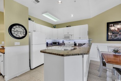 Kitchen with a peninsula, white appliances, a sink