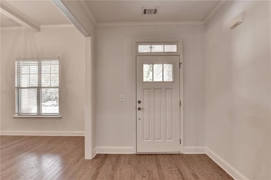 Foyer entrance with light wood-style flooring and crown molding