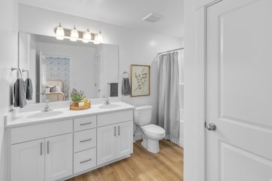 Bathroom featuring double vanity, light wood-style flooring, shower / bath combination with curtain, and ensuite bath