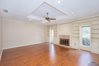 Unfurnished living room featuring ceiling fan, a tray ceiling, hardwood / wood-style floors, recessed lighting, and ornamental molding