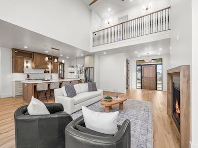 Living area featuring a warm lit fireplace, a towering ceiling, recessed lighting, light wood-type flooring, and ceiling fan