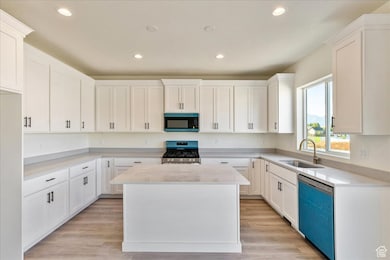 Kitchen featuring stainless steel gas stove, a center island, dishwashing machine, recessed lighting, and white cabinets