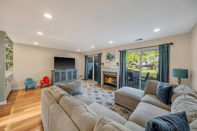 Living room with recessed lighting, light wood-type flooring, and a premium fireplace