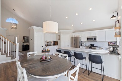 Dining room with high vaulted ceiling, dark wood-style floors, stairway, recessed lighting, and a chandelier