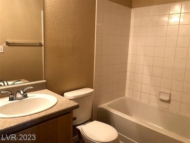 Bathroom with a textured wall, toilet, vanity, and