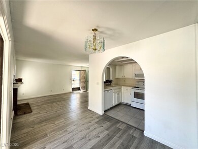 Kitchen featuring open floor plan, dark wood-type flooring, white appliances, and white cabinets