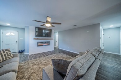 Living area featuring a glass covered fireplace, wood finished floors, recessed lighting, and ceiling fan