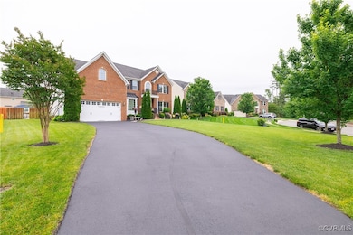 Garage, driveway, brick siding, and a front lawn