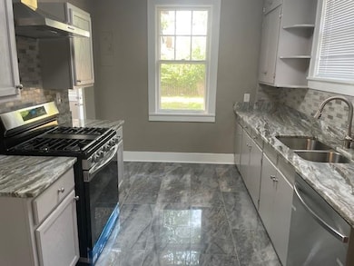 Kitchen featuring backsplash, white cabinets, wall