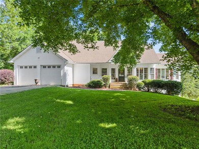 View of front facade with a front yard, driveway, a garage, and roof with shingles