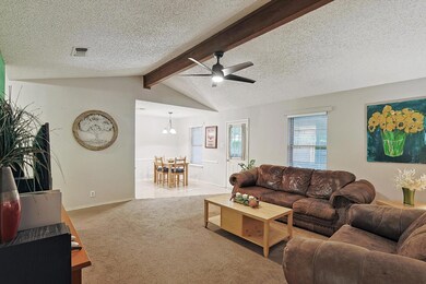 Carpeted living room with ceiling fan with notable chandelier, a textured ceiling, and lofted ceiling with beams