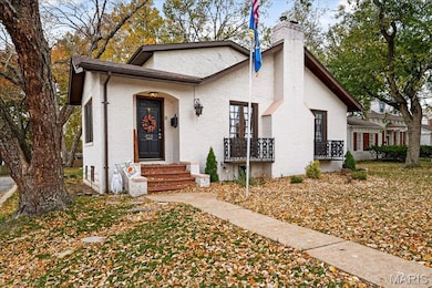 English style cottage style home with balcony arched covered porch and chimney.
