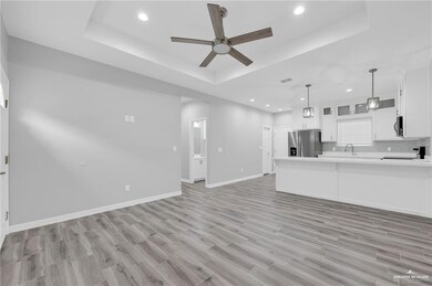 Unfurnished living room with a raised ceiling, a ceiling fan, light wood finished floors, and recessed lighting