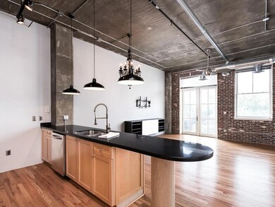 Kitchen featuring brick wall, a sink, light wood-style floors, a peninsula, and light brown cabinetry