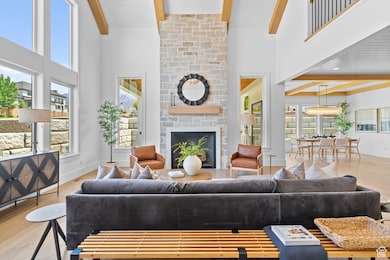 Living area featuring beam ceiling, wood finished floors, a high ceiling, and a large fireplace