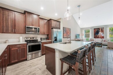 Kitchen featuring appliances with stainless steel finishes, a breakfast bar area, backsplash, open floor plan, and lofted ceiling